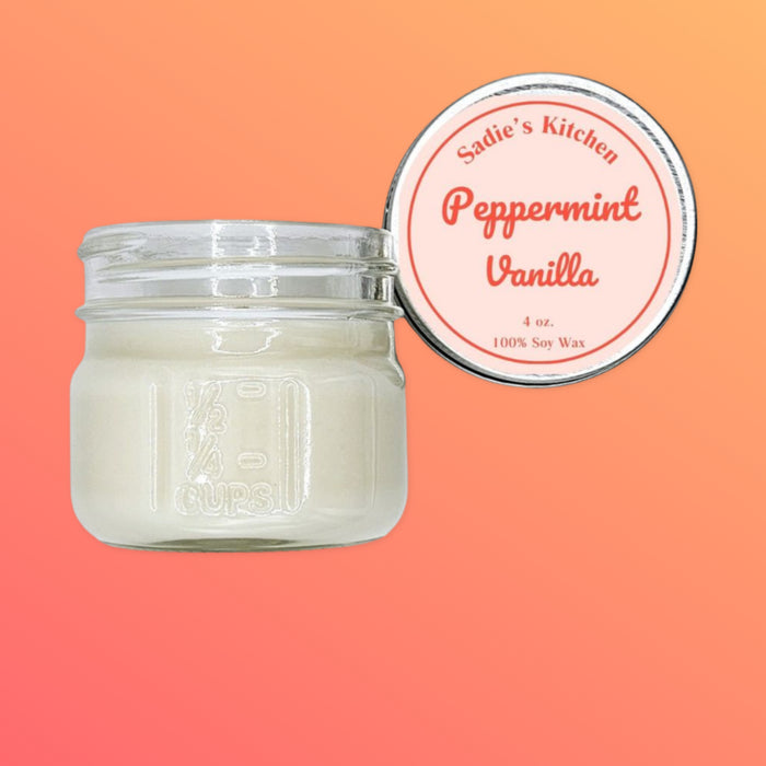 A white candle in a clear glass mason jar with a label that reads 'Peppermint Vanilla' and '100% Soy Wax'. The jar is placed on a background with a gradient of orange to white.
