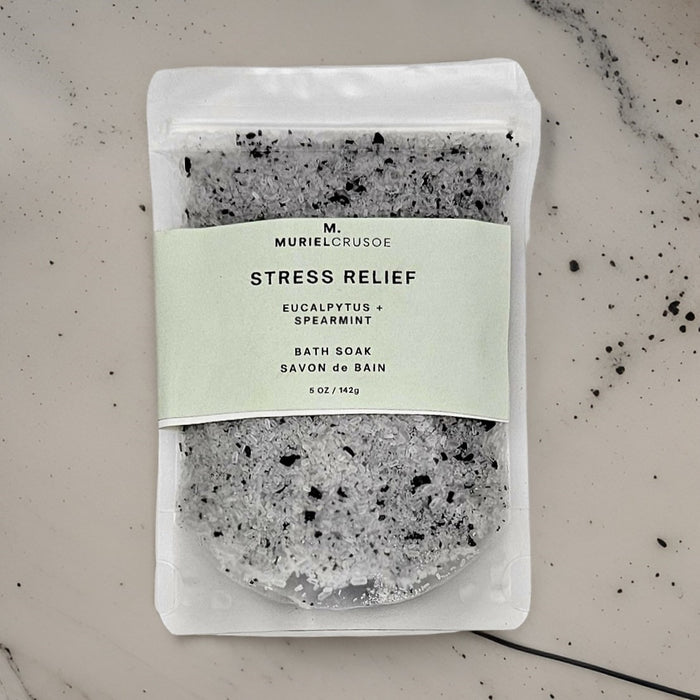A pouch of STRESS RELIEF bath soak with Eucalyptus and Spearmint, packaged on a marble background.
